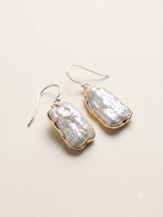 A pair of dangling baroque pearl earrings  set in silver gold plated bezels and hanging from thin silver-tone fishhook wires.

This product is not eligible for return